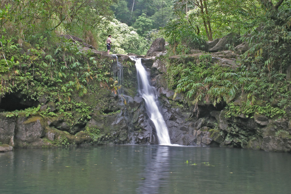 A visitor stands at the top of Waikamoi Stream's small waterfall, just a few steps from the road.